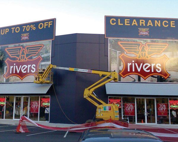 men on platform lift installing sign